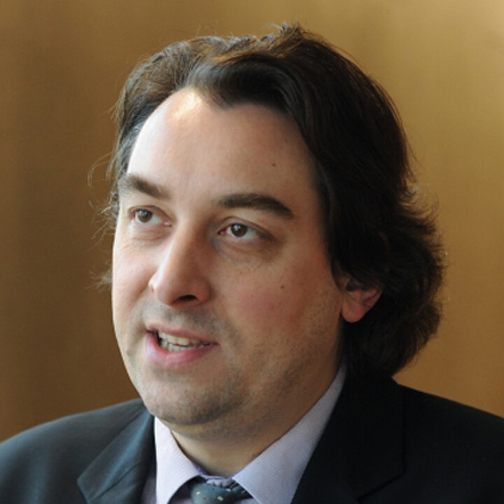 ciemnowłosy mężczyzna w średnim wieku w biznesowym stroju.